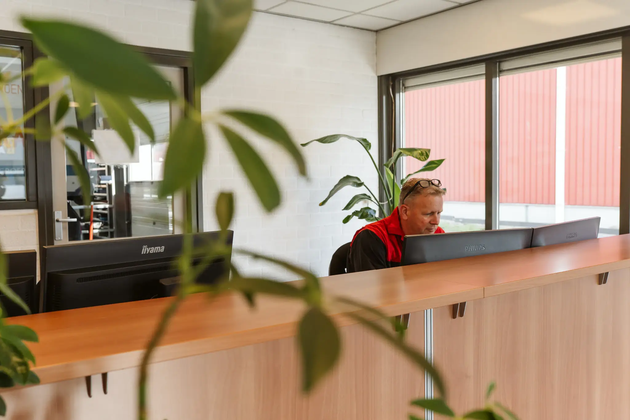 Medewerker aan het werk achter de computerschermen bij de balie.