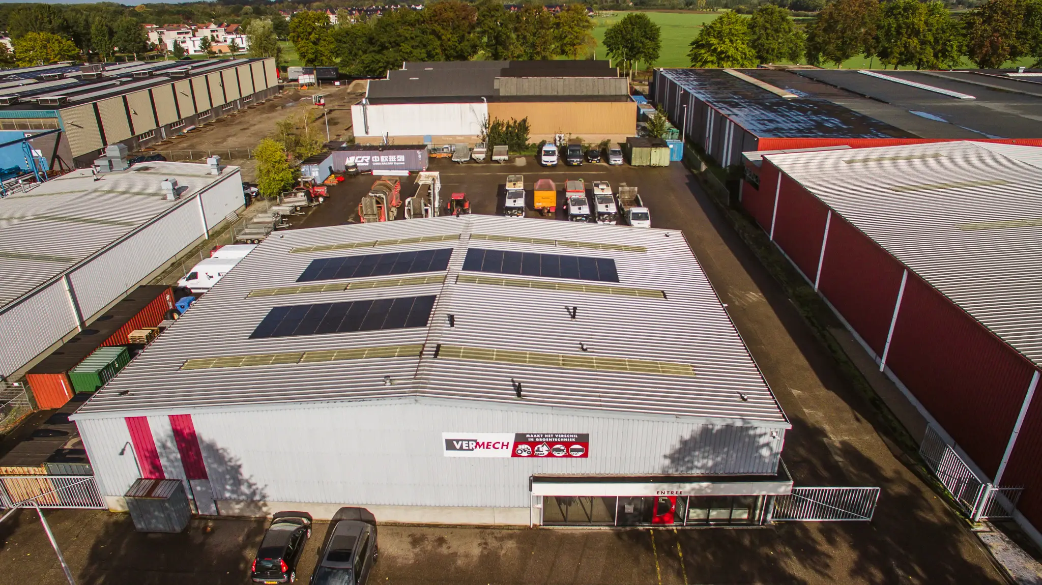 Luchtfoto van het Vermech-bedrijfspand met zonnepanelen en machines op het achterterrein.