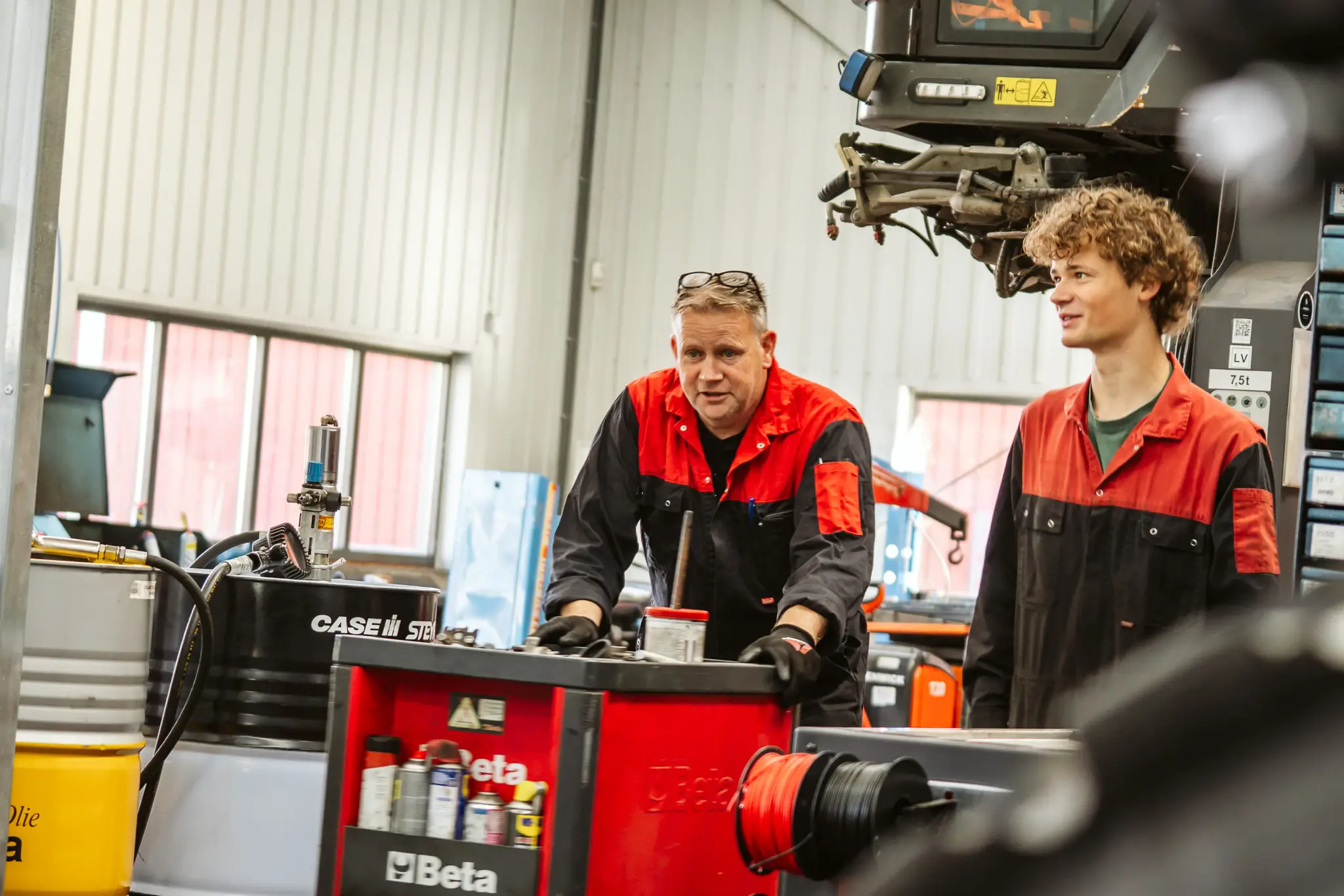 Een ervaren en een jonge monteur overleggen in de werkplaats
