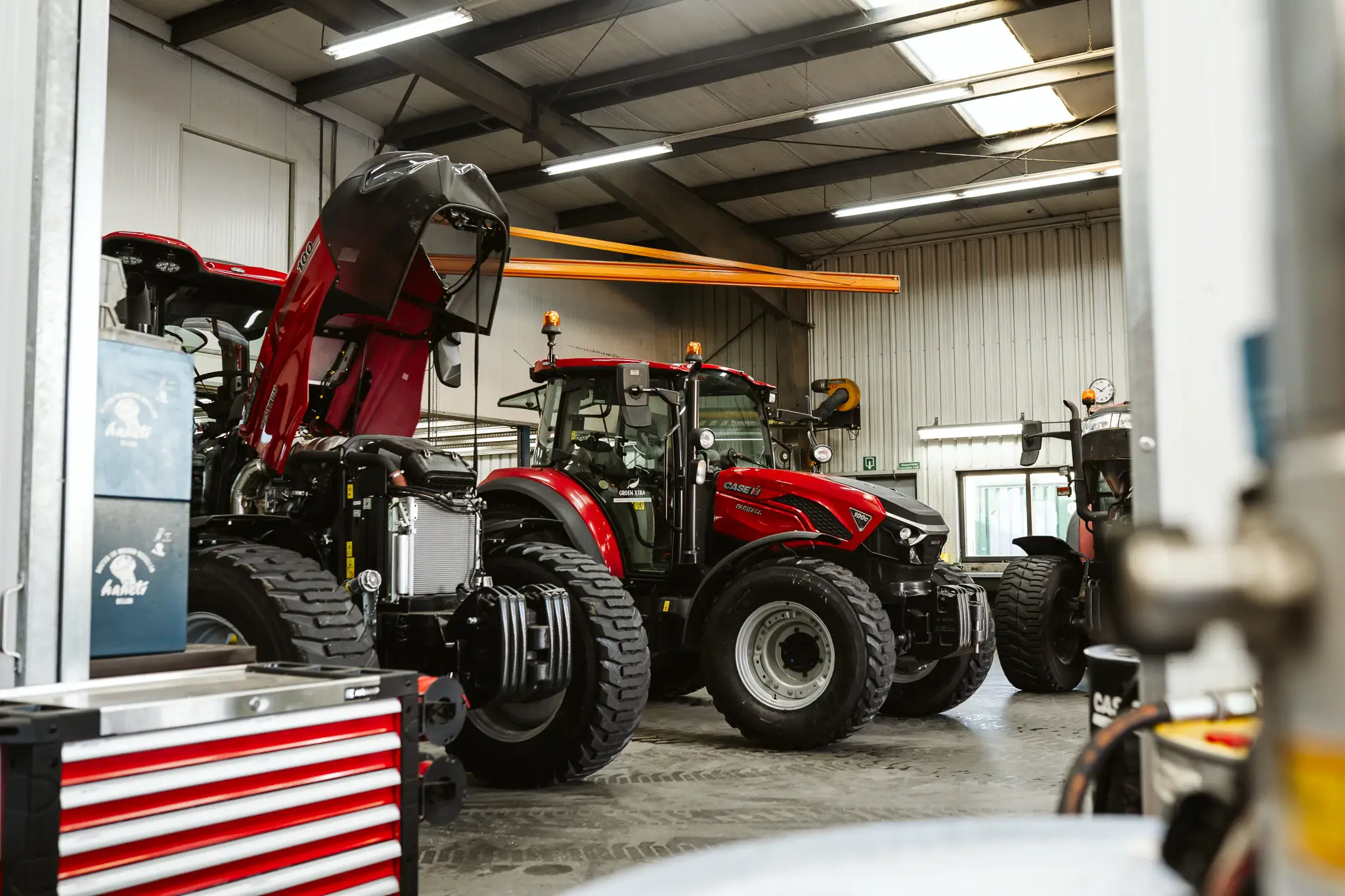 Rode Case IH-tractoren in de werkplaats, waarvan één met geopende motorkap.